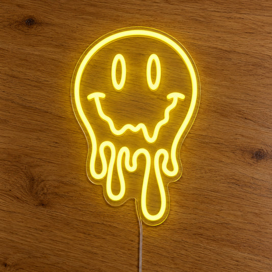 Melting Smiley Face LED Neon Light Sign in yellow, featuring dripping smiley-face outline on a wooden surface.