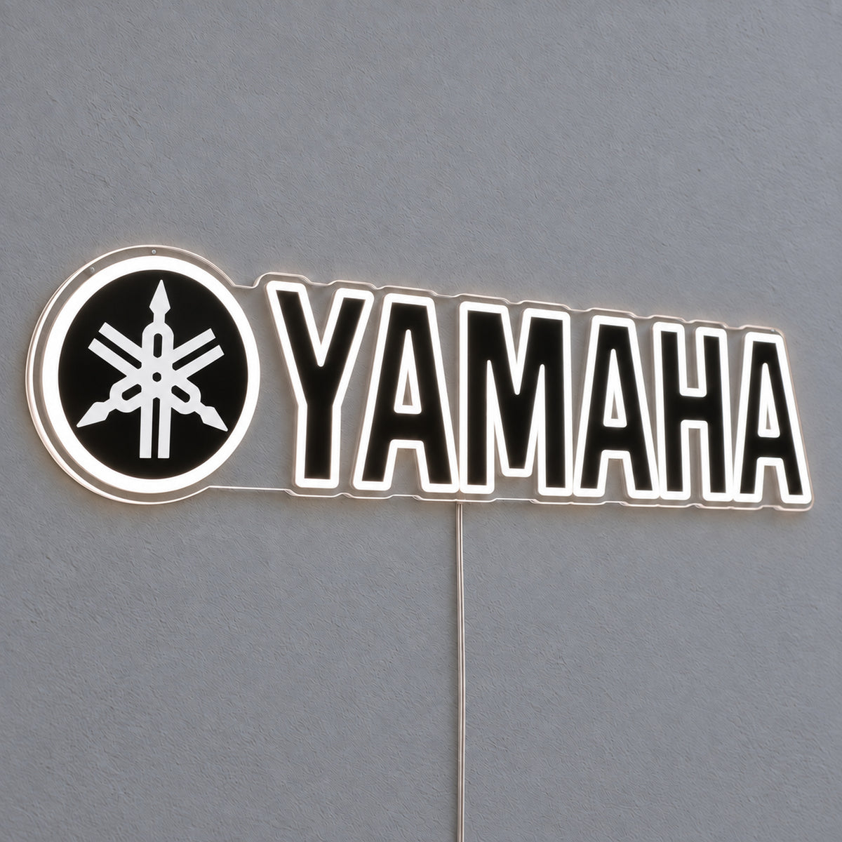 Yamaha (Black) LED Neon Sign in white, featuring Yamaha lettering beside a tuning-fork emblem on a grey wall.