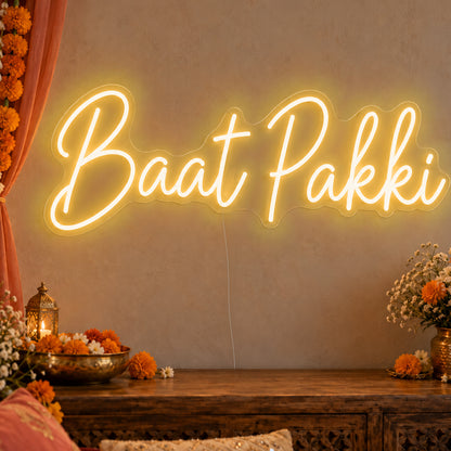 Baat Pakki Neon Sign in gold LED neon on clear acrylic, angled view