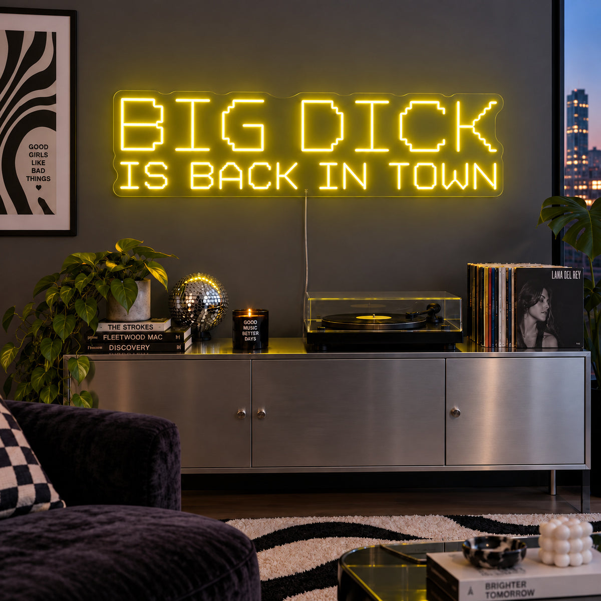 Big Dick Is Back In Town Neon Sign with yellow lighting, displayed above a record player and metal sideboard.
