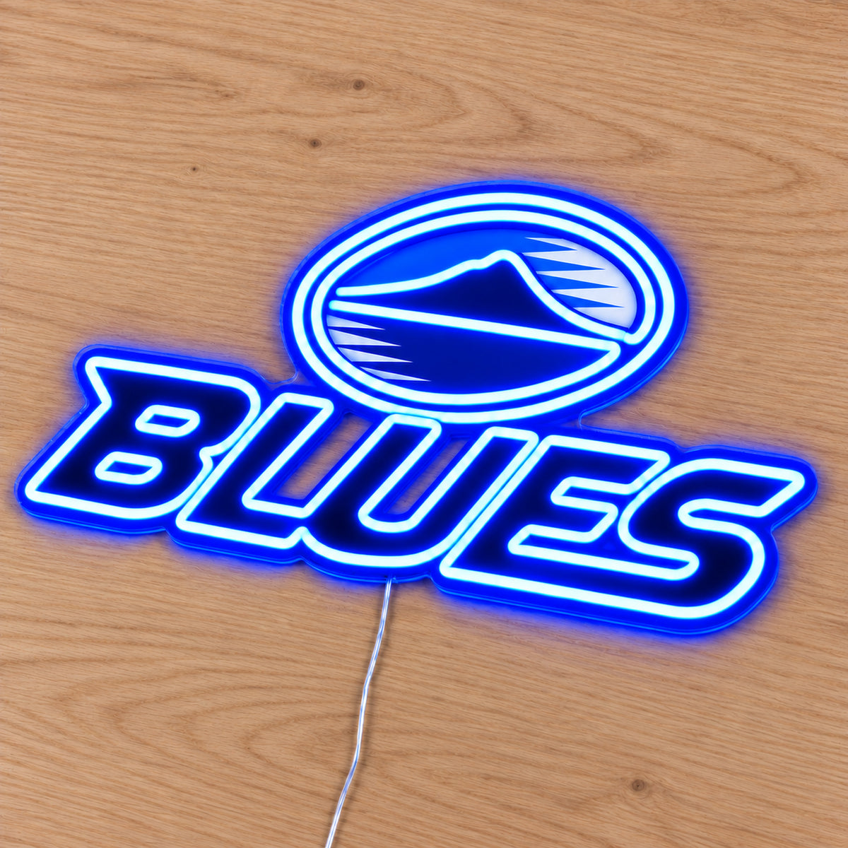 Blues neon sign with blue LED neon lying flat on light wood, second angle