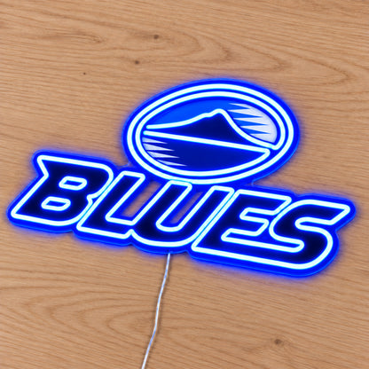 Blues neon sign with blue LED neon lying flat on light wood, second angle