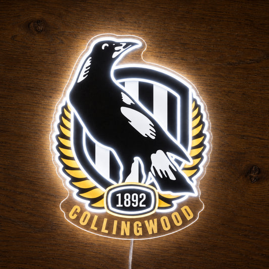 Collingwood Magpies neon sign glowing brightly on a wooden surface in dim lighting