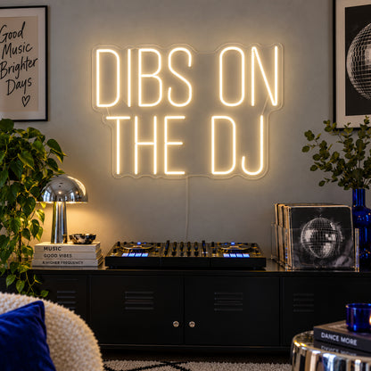 Warm White version of the Dibs On The DJ Neon Sign, shown above a home DJ setup.