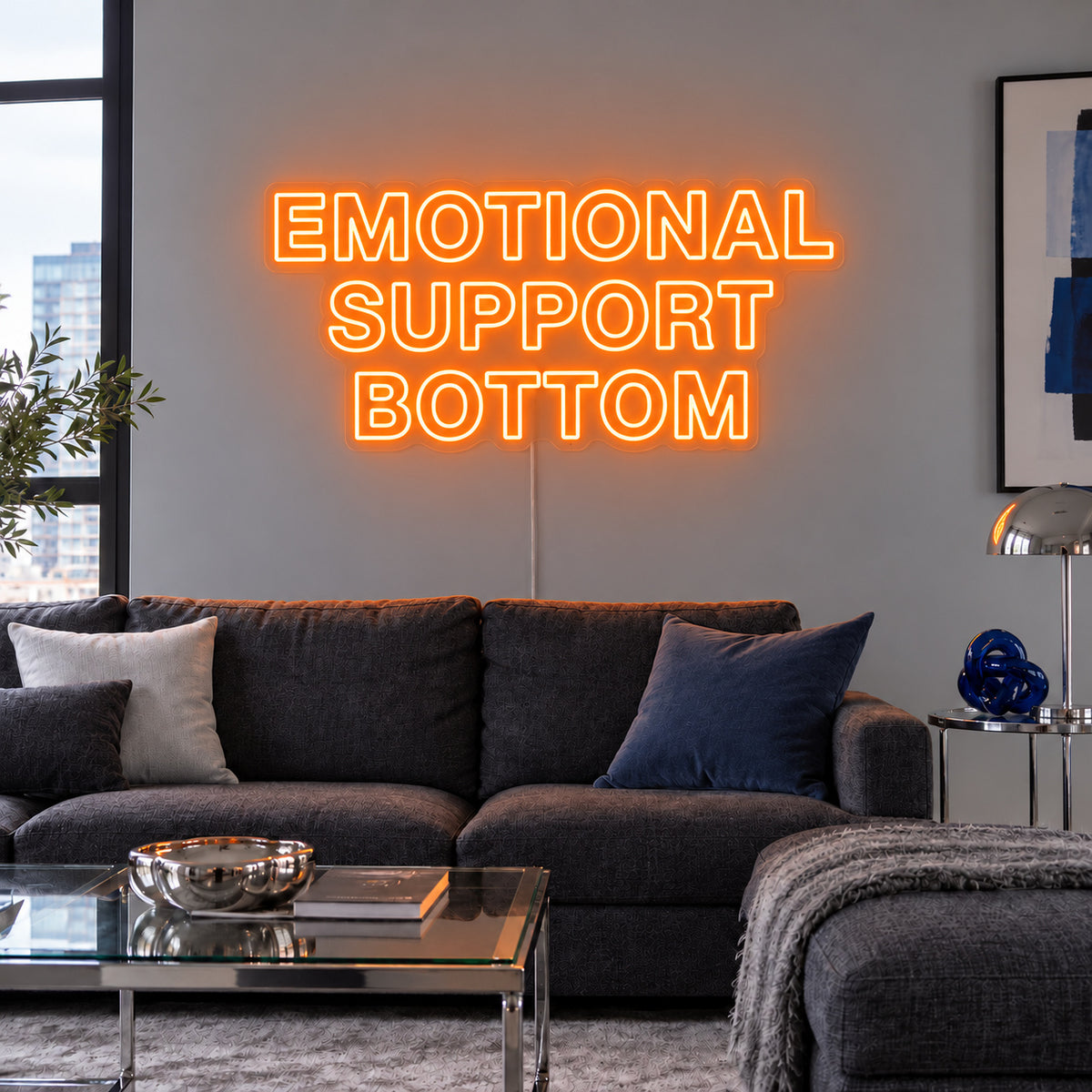 Orange version of the Emotional Support Bottom Neon Sign, shown above a charcoal sofa.