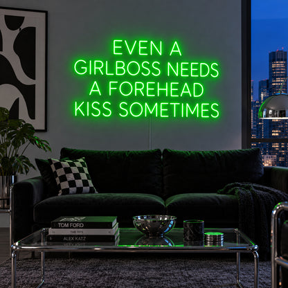 Even A Girlboss Needs A Forehead Kiss Sometimes Neon Sign with green lighting, displayed above a dark sofa and mirrored coffee table.