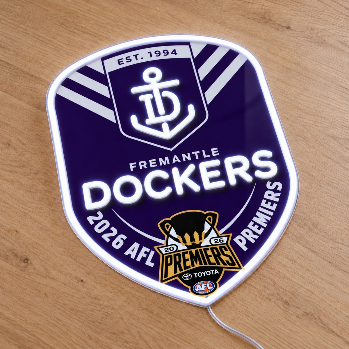 Fremantle Dockers 2026 AFL Premiers LED neon sign on a wooden surface, viewed at an angle