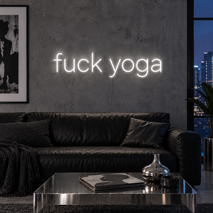 Fuck Yoga Neon Sign in white, featuring Fuck Yoga lettering above a black leather sofa.