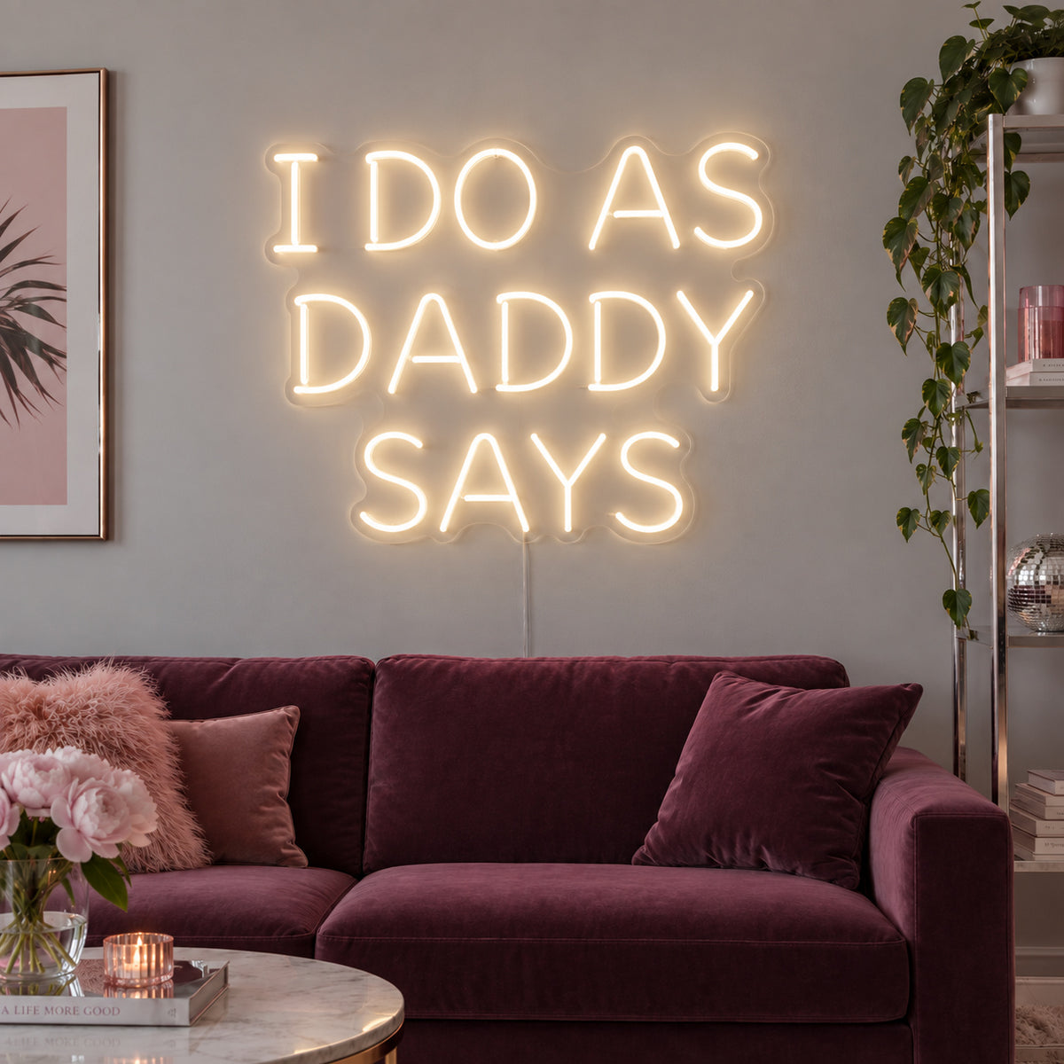 Warm White version of the I Do As Daddy Says Neon Sign, shown above a burgundy sofa.