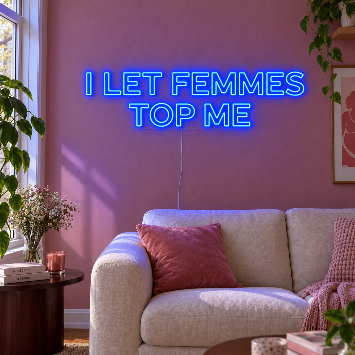 I Let Femmes Top Me Neon Sign glowing blue in outlined lettering above a cream chair.