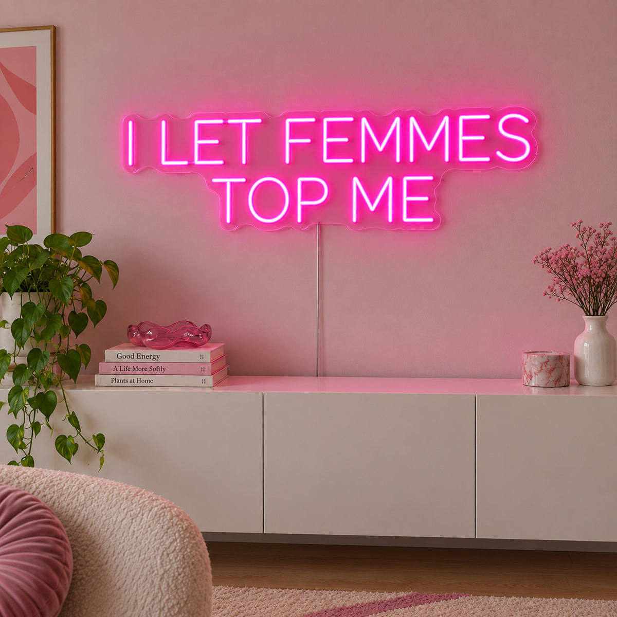 Rose Red version of the I Let Femmes Top Me Neon Sign, shown in rounded lettering above a white sideboard.