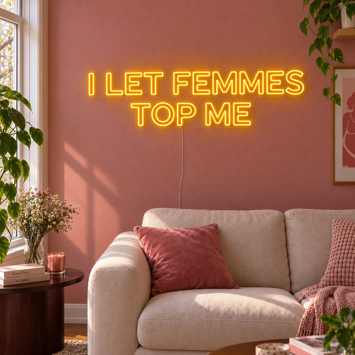 I Let Femmes Top Me Neon Sign glowing gold in outlined lettering above a cream chair.