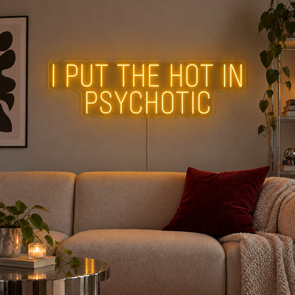 I Put The Hot In Psychotic Neon Sign glowing gold above a neutral sofa.