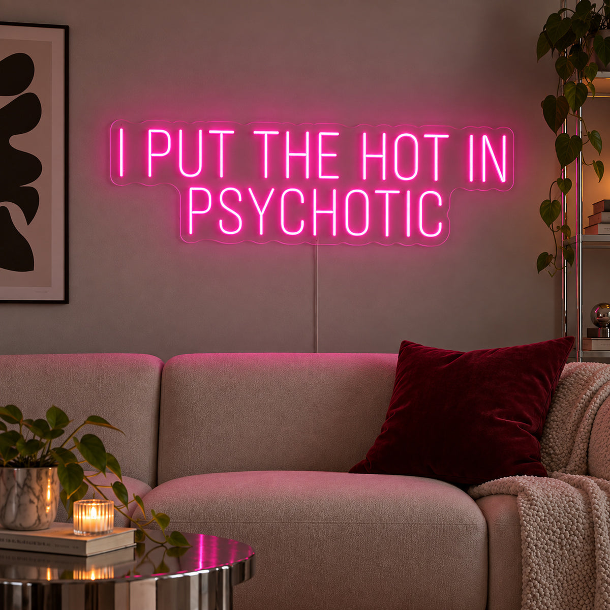 I Put The Hot In Psychotic Neon Sign glowing pink above a neutral sofa.