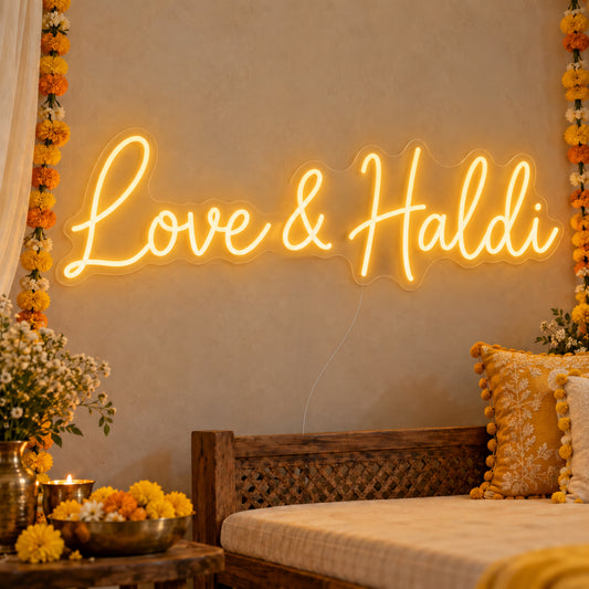 Love Haldi Neon Sign on clear cut-to-shape acrylic, illuminated on a wall in a styled celebration setting