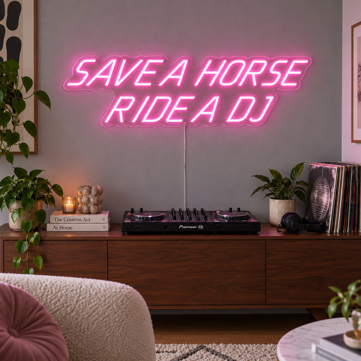 Save A Horse Ride A DJ Neon Sign glowing pink above a turntable on a wooden sideboard.