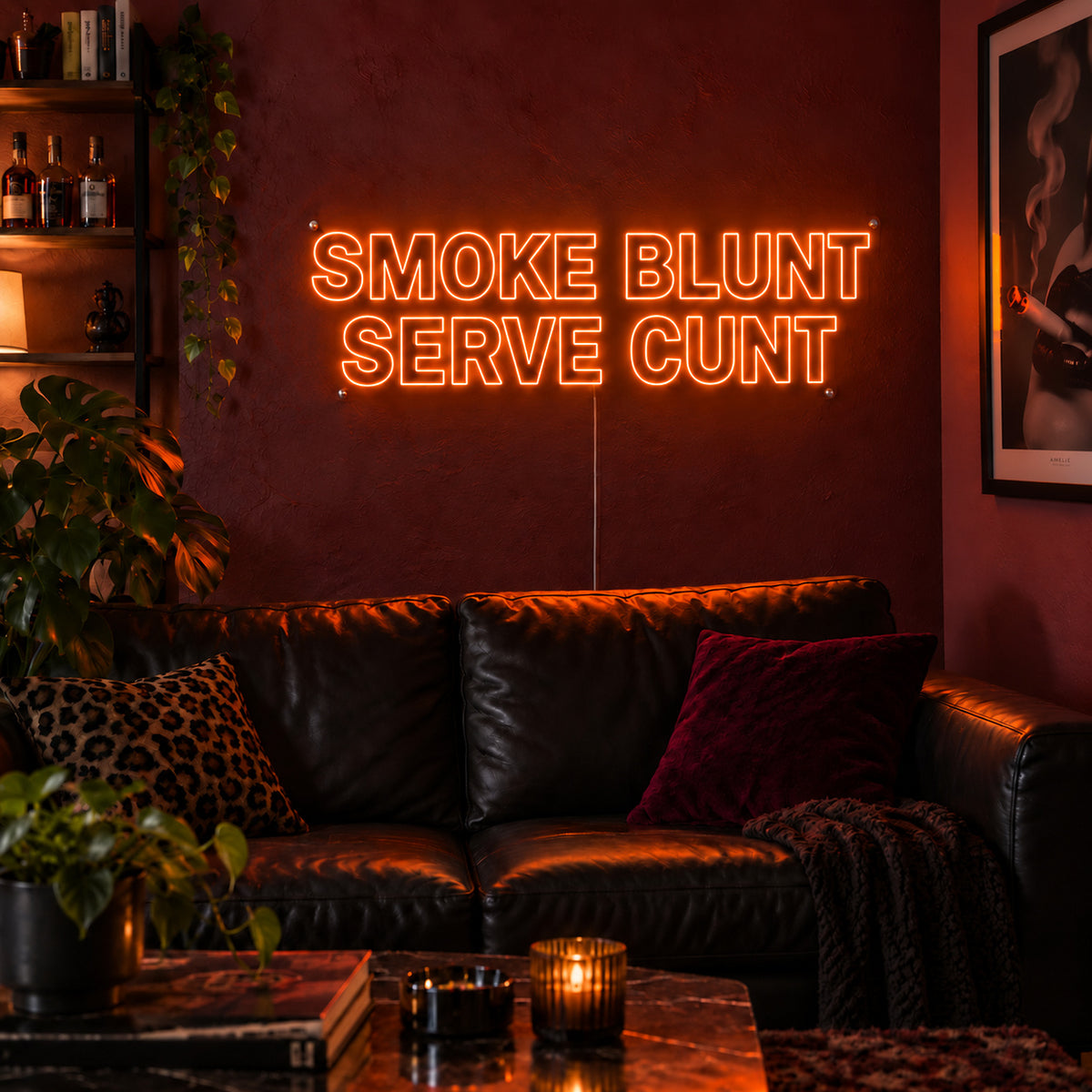 Orange version of the Smoke Blunt Serve Cunt Neon Sign, shown above a black leather sofa.