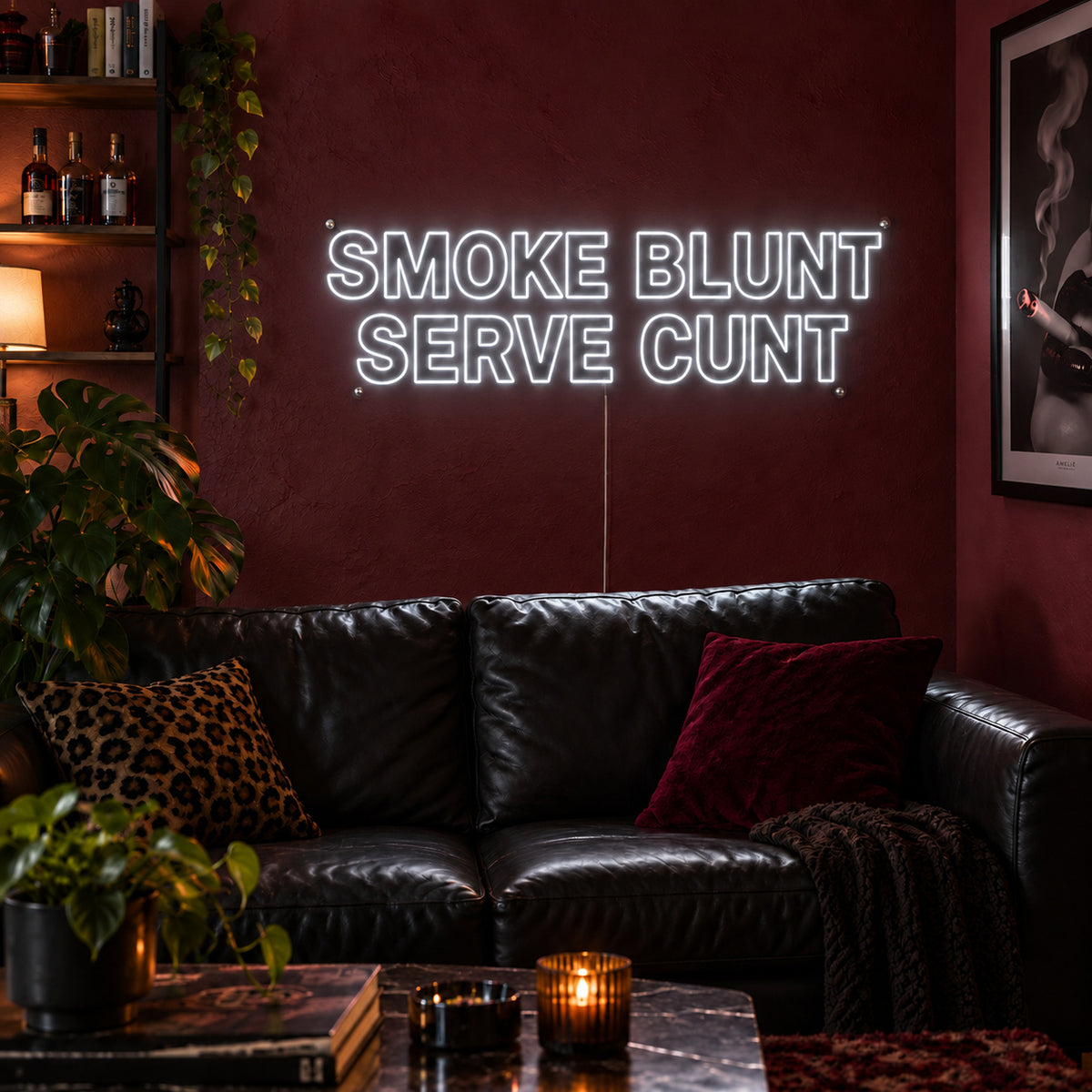 Smoke Blunt Serve Cunt Neon Sign glowing white above a black leather sofa.