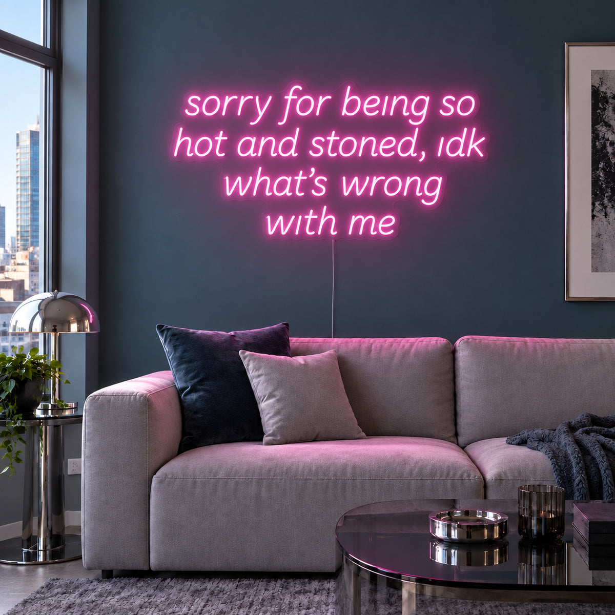 Sorry For Being So Hot And Stoned, Idk What's Wrong With Me Neon Sign glowing pink above a grey sofa against a blue wall.